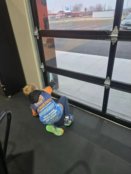 Crew member cleaning a commercial glass garage door