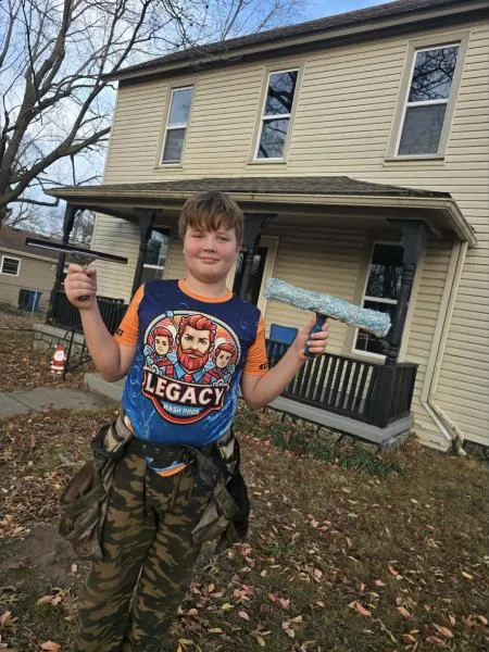 Young crew member holding a squeegee in front of a house