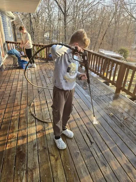 Crew member pressure washing a wooden deck